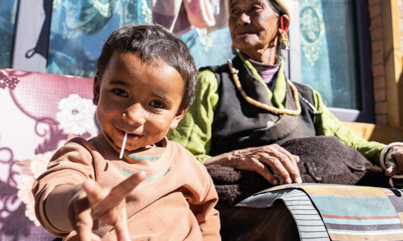 An elder and a child bask at the new Daman Village in Jilung Town of Xigaze in southwest China's Xizang Autonomous Region, Dec. 15, 2024. The new Daman Village, about 30-kilometer away from the China-Nepal border, is the only habitat of Daman people in China. The living condition in the village has been improved substantially in recent years. A series of homestay facilities under construction there are expected to boost the local annual per capita income to 2,000 yuan (about 275 U.S. dollars) when operational. (Xinhua/Tenzin Nyida)