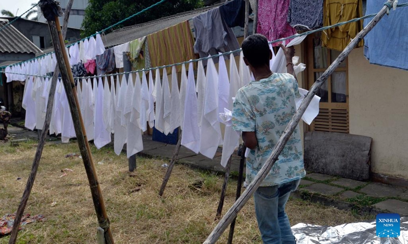 A laundry worker collects dried cloths at a community named Laundrywatte in Colombo, Sri Lanka on Dec. 13, 2024. (Photo: Xinhua)