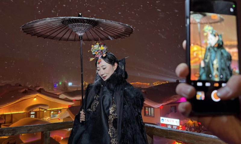 A tourist poses for photos at a snow town scenic area in Hailin City, northeast China's Heilongjiang Province, Dec. 28, 2024. Located in Hailin City of Heilongjiang Province, the scenic area has seen a peak of tourism recently with the average number of daily visitors exceeding 20,000. (Xinhua/Yang Siqi)