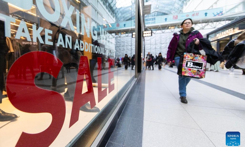 A woman walks past a store with a Boxing Day promotion sign in Toronto, Canada, on Dec. 26, 2024. (Photo by Zou Zheng/Xinhua)