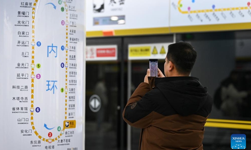 A passenger takes photos of the map of subway line 8 in Xi'an, northwest China's Shaanxi Province, Dec. 26, 2024. The newly-opened line 8, the first subway loop line with 37 stations in Xi'an, brought the length of the city's metro system to over 400 km. (Xinhua/Zou Jingyi)