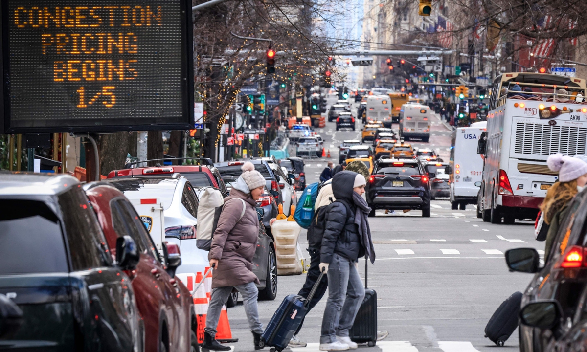 Pedestrians walk past a congestion pricing warning sign on 5th Avenue in New York on January 5, 2025 as congestion pricing begins taking effect in New York City. The city revived this controversial scheme to charge drivers entering parts of the city, a first in the US. Photo: VCG