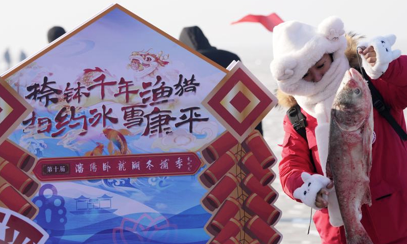 A tourist holds a fish to pose for photos at Wolong Lake in Kangping County of Shenyang, northeast China's Liaoning Province, Jan. 11, 2025. A winter fishing-themed cultural and tourism season began here on Saturday. (Xinhua/Li Gang)