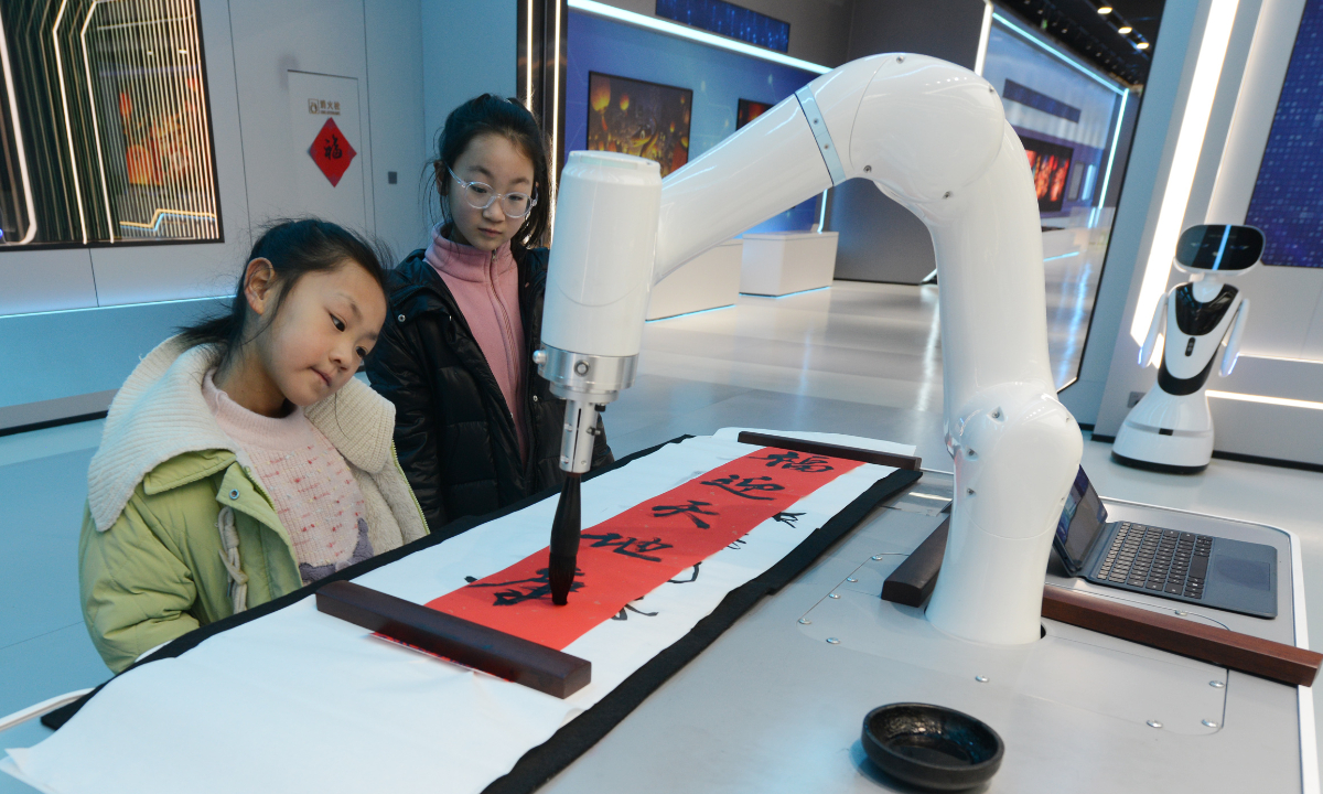 Children watch a robot doing calligraphy for Spring Festival couplets at a digital innovation center in Zhengzhou, Central China's Henan Province, on January 19, 2025. A digital Spring Festival event opened on the same day, using virtual reality, augmented reality and other technologies to recreate cultural scenes. Attendees can experience the integration of traditional culture and technology through wearable devices. Photo: VCG