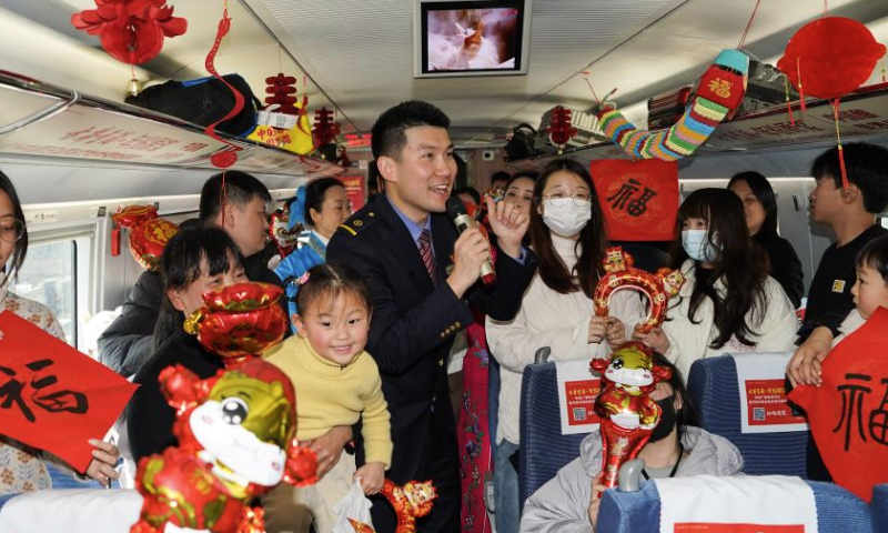A staff member interacts with passengers on train C3685, east China's Anhui Province, Jan. 13, 2025. The Hefei branch of China Railway Shanghai Bureau Group Co., Ltd. organized railway staff to demonstrate local intangible cultural heritages on the train, adding festive atmosphere to the upcoming Spring Festival travel rush. (Xinhua/Du Yu)