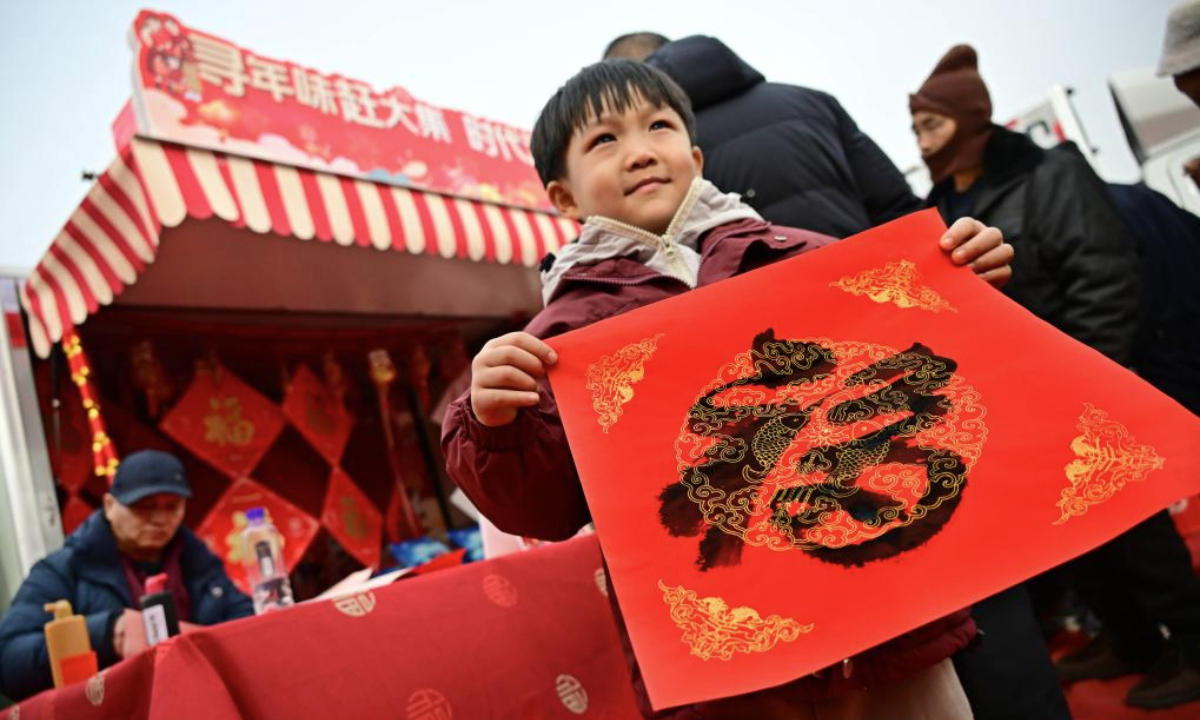 A boy receives a calligraphy work of Chinese character Fu, which means good fortune, at the Poli Market in Qingdao Xihai'an (West Coast) New Area in Qingdao, east China's Shandong Province, Jan. 18, 2025. With a history of more than 300 years, the Poli Market is a local intangible cultural heritage and one of the biggest traditional markets in eastern Shandong Province. As the Spring Festival approaches, many visitors flock to the market for abundant new year decorations, agricultural products, local delicacies and so on. (Xinhua/Li Ziheng)