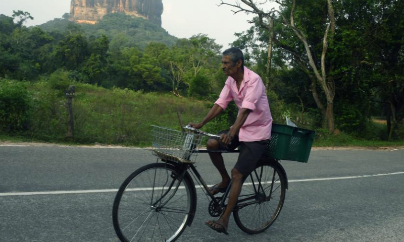 A man rides a bike past the Sigiriya Lion Rock, a popular tourist spot, in Dambulla, Sri Lanka, Jan. 17, 2025. The ancient city of Sigiriya was inscribed as a world heritage site by United Nations Educational, Scientific and Cultural Organizations (UNESCO) in 1982. (Photo by Ajith Perera/Xinhua)