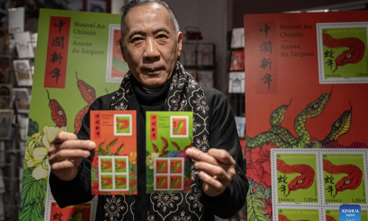 Chen Jianghong, a French artist of Chinese, origin also the designer of the stamps, displays the Year of the Snake commemorative stamps during a launching ceremony in Paris, France, Jan. 18, 2025. French post office, La Poste, on Saturday issued two stamps to celebrate the upcoming Chinese New Year, the Year of the Snake, which starts on Jan. 29, 2025. (Photo by Aurelien Morissard/Xinhua)