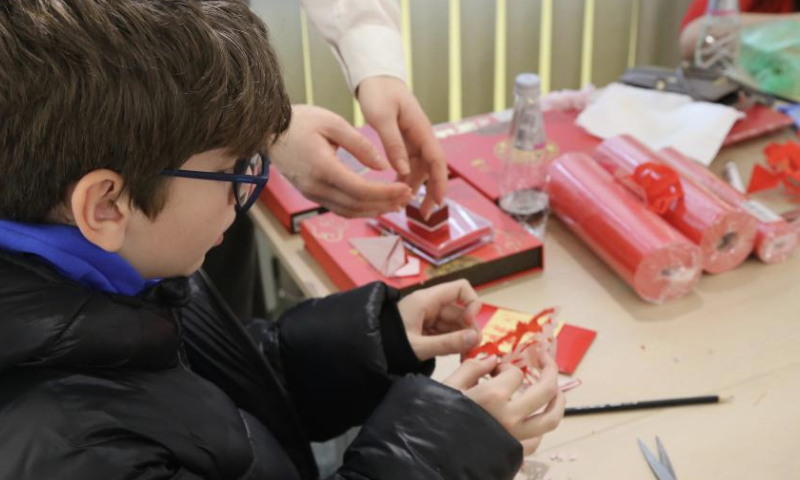 A Bulgarian boy tries to make Chinese paper cutting works during a celebration dedicated to the upcoming Spring Festival in Sofia, Bulgaria, on Jan. 12, 2025. (Photo by Marian Draganov/Xinhua)