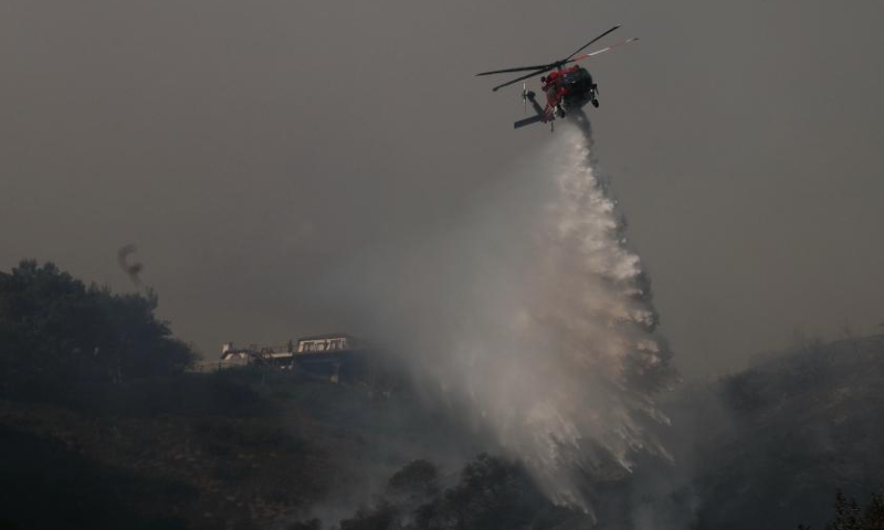 A firefighting helicopter drops water to prevent the wildfire from spreading further on the hills of Mandeville Canyon in Los Angeles, California, the United States, on Jan. 11, 2025. At least 16 people have been killed by blazes as thousands of firefighters race to battle spreading wildfires across Los Angeles County, the most populous U.S. county, local authorities said Saturday. (Photo by Qiu Chen/Xinhua)