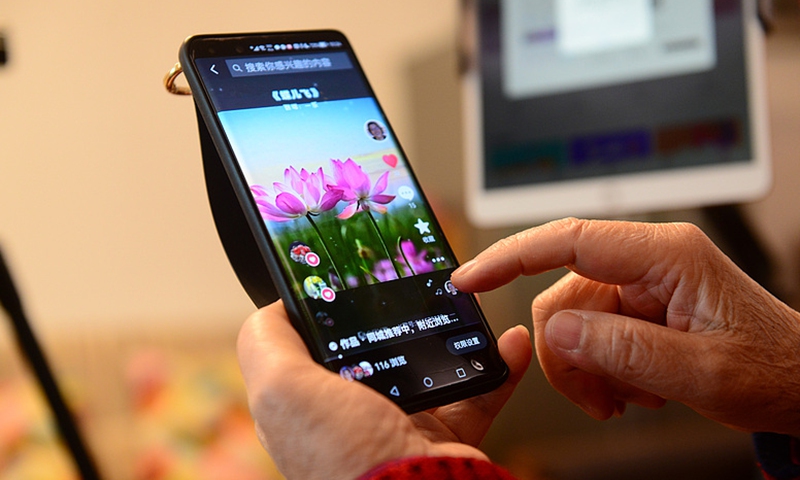 An elderly person scrolls through a social media platform on her mobile phone. Photo: VCG