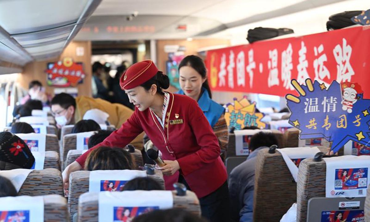 A train crew member distributes souvenirs to passengers on C2114 train in Tianjin on January 14, 2025. Chinese travelers packed into cars, trains and planes on Tuesday, kicking off the landmark chunyun. Photo: VCG