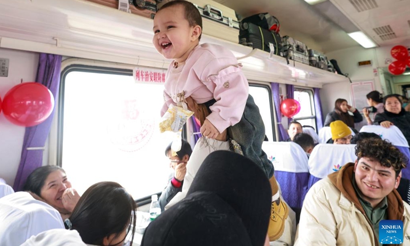 A passenger plays with a child on the train No. 7557 from Urumqi to Hotan Prefecture in northwest China's Xinjiang Uygur Autonomous Region, Jan. 2, 2025. (Xinhua/Wang Fei)