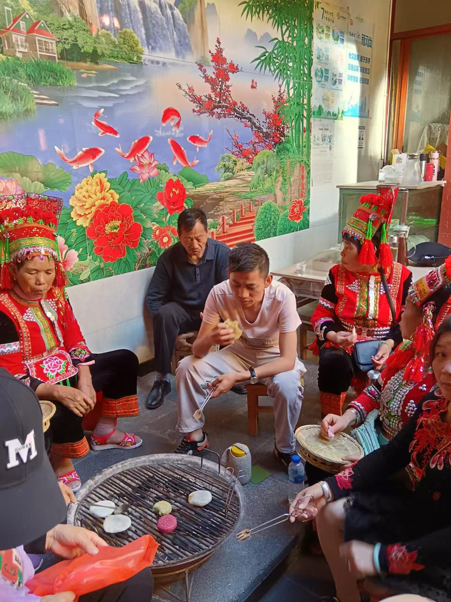Li Fashun enjoys traditional delicacy rice cakes along with families and friends at his home in Simola Wa village, Southwest China's Yunnan Province. Photo: Courtesy of Li