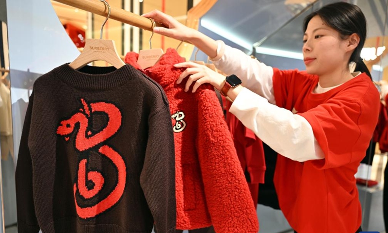 A sales person arranges snake-themed clothes at Haikou International Duty-free Shopping Complex in Haikou, south China's Hainan Province, Dec. 31, 2024. (Xinhua/Guo Cheng)