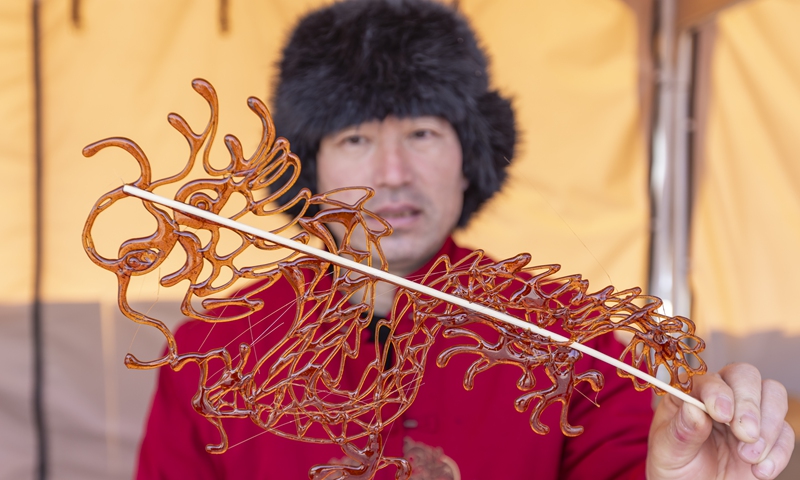 A representative inheritor of the intangible cultural heritage of sugar-figurine craftsmanship showcases a dragon sugar figurine at a fair in Yuncheng, North China's Shanxi Province, on February 6, 2025. The activity allows the public to appreciate the unique charm of intangible cultural heritage. Photo: VCG