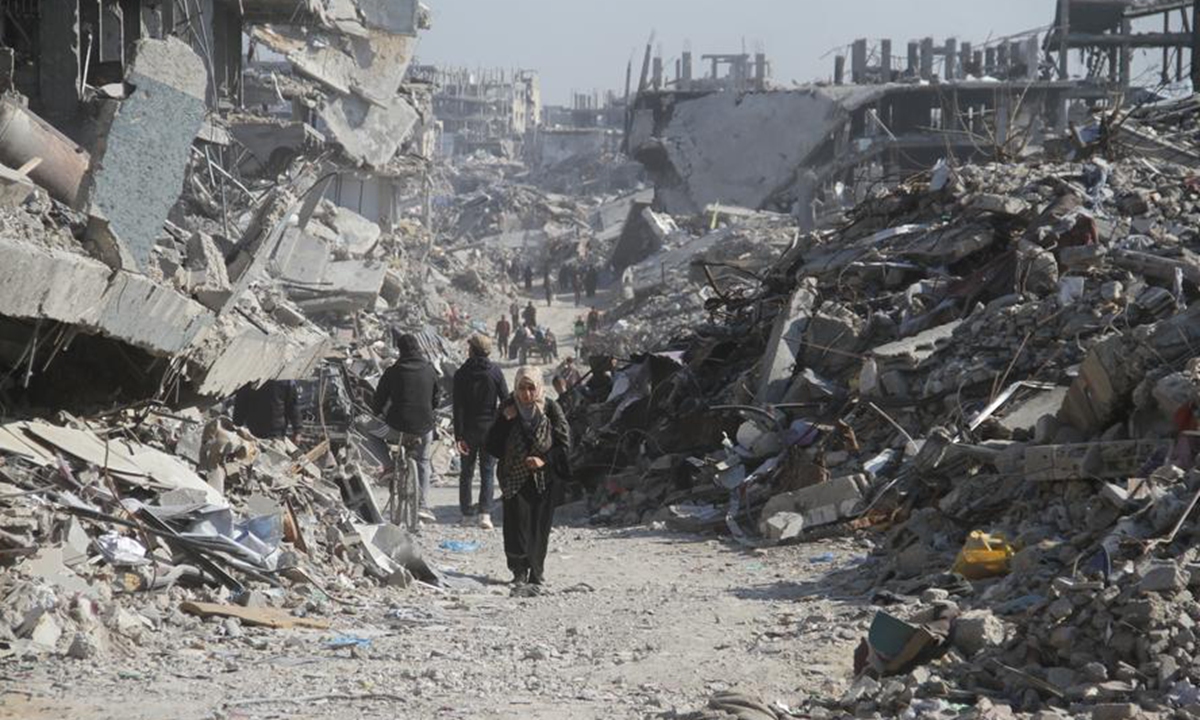Palestinians are seen on a street with destroyed buildings in Jabalia refugee camp in the northern Gaza Strip, on Jan. 29, 2025. (Photo by Abdul Rahman Salama/Xinhua)
