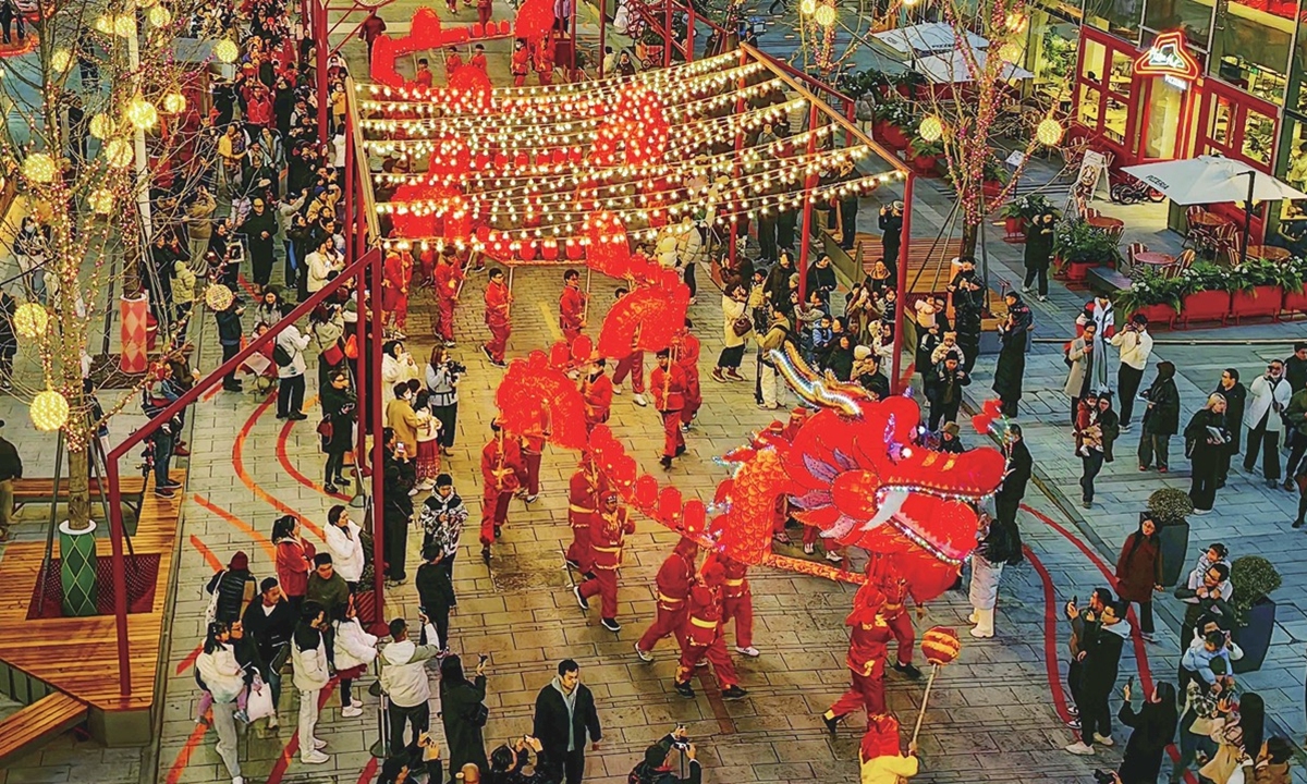 Pedestrians watch a traditional dragon dance on a shopping street in downtown Shanghai on January 18, 2025. Photo: VCG