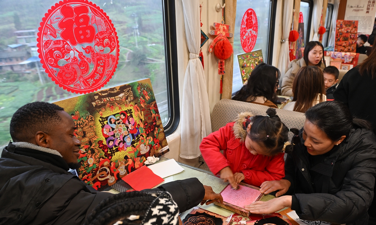 Foreigners take part in a Qijiang Farmers' Woodcut Printing activity on a train on February 12, 2025. The China Railway Chengdu Group has collaborated with Chongqing authorities to host a themed event bringing intangible cultural heritage to train carriages. Passengers have the chance to admire the lively artworks and even craft their own prints. Photo: VCG