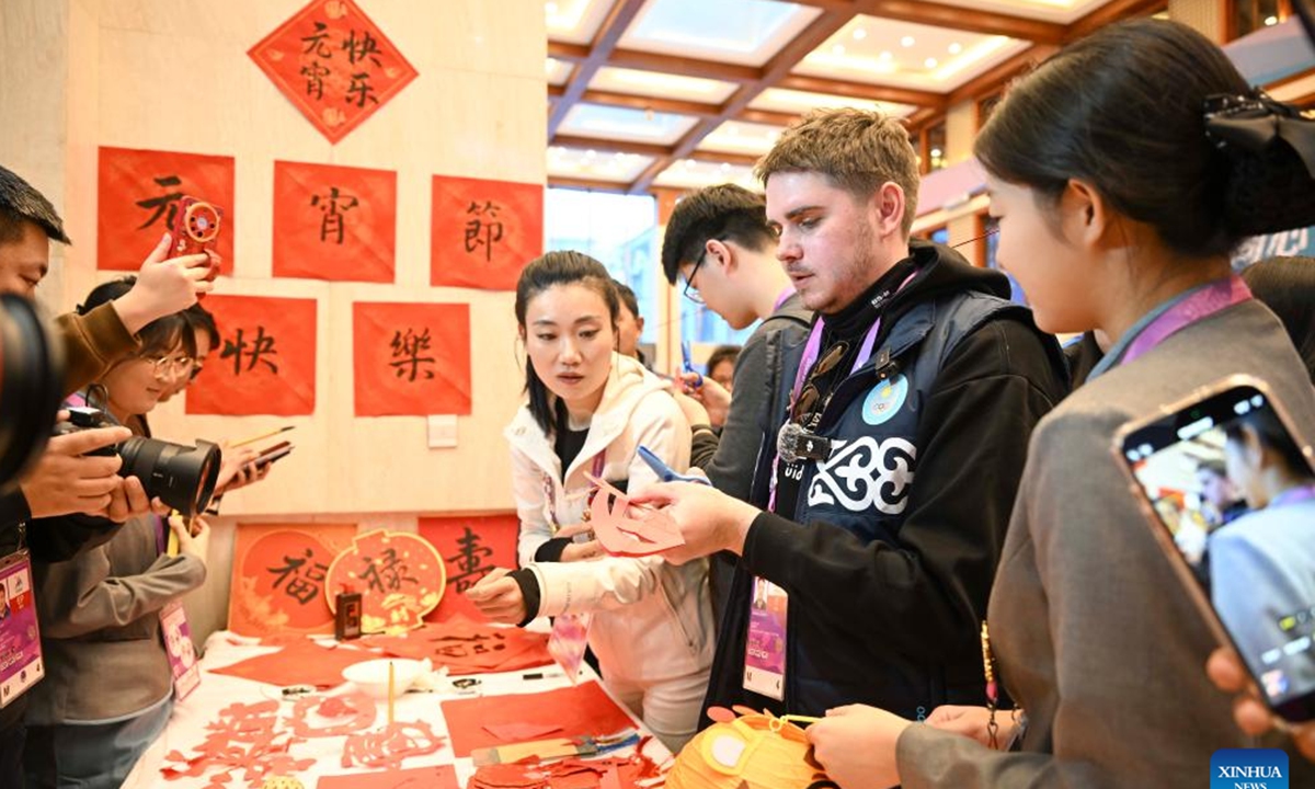 A journalist from Kazakhstan tries paper cutting at an activity to celebrate the Lantern Festival at press center for the 9th Asian Winter Games in Yabuli, northeast China's Heilongjiang Province, Feb. 12, 2025. (Xinhua/Hu Huhu)
