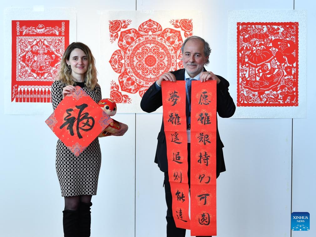 UN staff members Rita Franceschet (L) and Abdel Wahab Hani pose for a photo with Chinese calligraphy works during an event celebrating the Chinese Spring Festival at the Palais des Nations in Geneva, Switzerland, Feb. 12, 2025. This event featuring Tai Chi fan performances, paper-cutting, calligraphy, and lantern riddles was held here on Wednesday. It was organized by the Permanent Mission of China to the UN Office in Geneva and other international organizations in Switzerland. (Photo: Xinhua)
