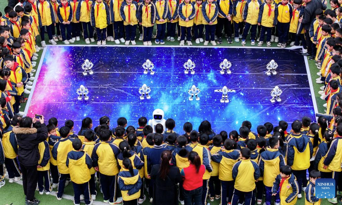 An aerial drone photo shows students interacting with robots at a primary school in Xingye County of Yulin, south China's Guangxi Zhuang Autonomous Region, Feb. 17, 2025. With a mixture of nerves and excitement, many students in China attended their special first class of new semester. (Xinhua/Cao Yiming)