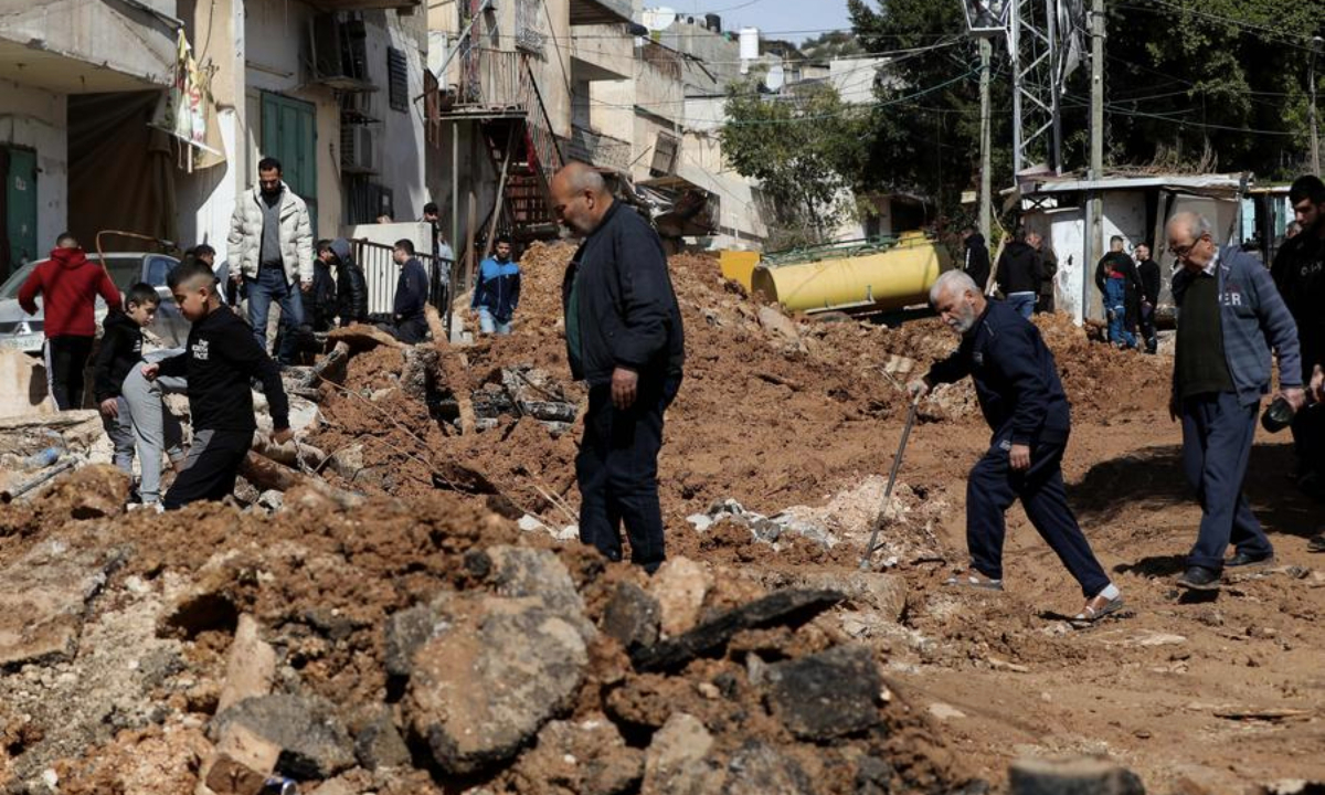 Palestinian people cross a street destroyed in an Israeli military operation at Al-Fara'a refugee camp in the West Bank city of Tubas, on Feb. 14, 2025. (Photo by Ayman Nobani/Xinhua)