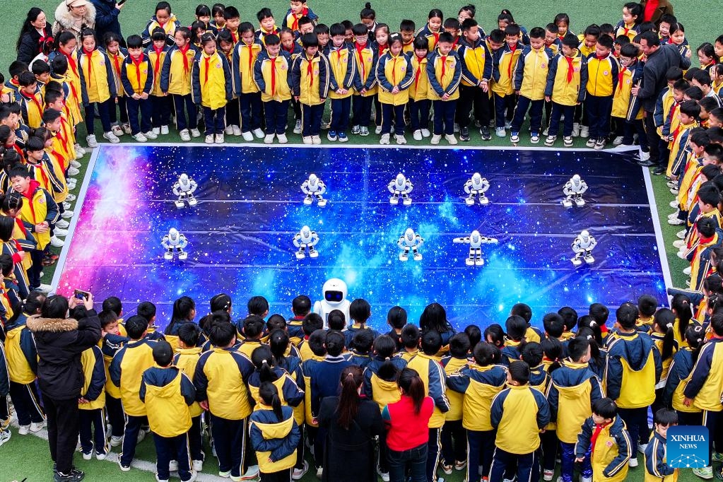 An aerial drone photo shows students interacting with robots at a primary school in Xingye County of Yulin, south China's Guangxi Zhuang Autonomous Region, Feb. 17, 2025. With a mixture of nerves and excitement, many students in China attended their special first class of new semester. (Photo: Xinhua)