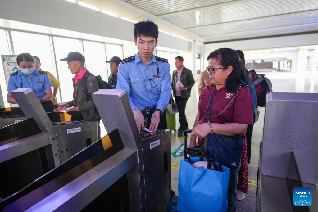 Staff members help tourists from Laos and Thailand pass a ticket barrier at the Xishuangbanna railway station in Jinghong City, Xishuangbanna Dai Autonomous Prefecture, southwest China's Yunnan Province, Feb. 18, 2025. After entering through Mohan Port, a tourist group of 15 people from Laos and Thailand took a train and arrived in Jinghong City, Xishuangbanna Dai Autonomous Prefecture on Tuesday. It was the first tourist group to arrive since the implementation of the visa-free policy allowing tourist groups from ASEAN (the Association of Southeast Asian Nations) countries to enter Xishuangbanna. (Photo: Xinhua)