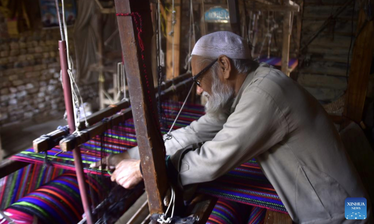 A man makes traditional shawls at a local shop on the outskirts of northwest Pakistan's Peshawar on Feb. 26, 2025. (Photo by Saeed Ahmad/Xinhua)