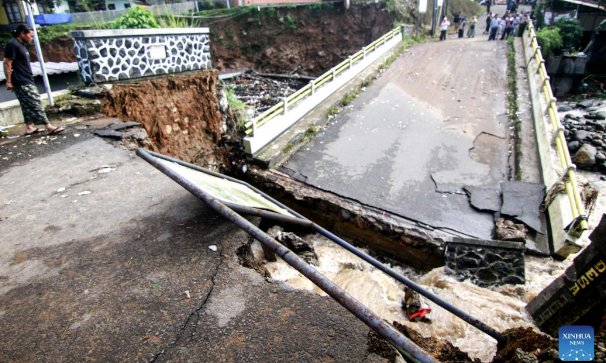 People stand near a damaged bridge after heavy rain and overflow of Ciliwung river hit Cisarua village in Bogor Regency, Central Java, Indonesia, March 3, 2025. (Photo by Sandika Fadilah/Xinhua)

