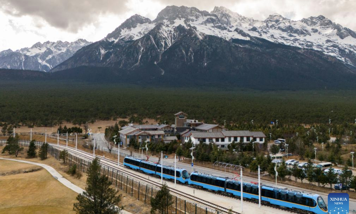 A drone photo shows a sightseeing train running near a snow mountain in southwest China's Yunnan Province, Feb. 25, 2025. A sightseeing train connecting Lijiang ancient town and Yulong Snow Mountain was launched here this February, becoming a new tourism hot spot in northwest Yunnan. (Photo by Peng Yikai/Xinhua)