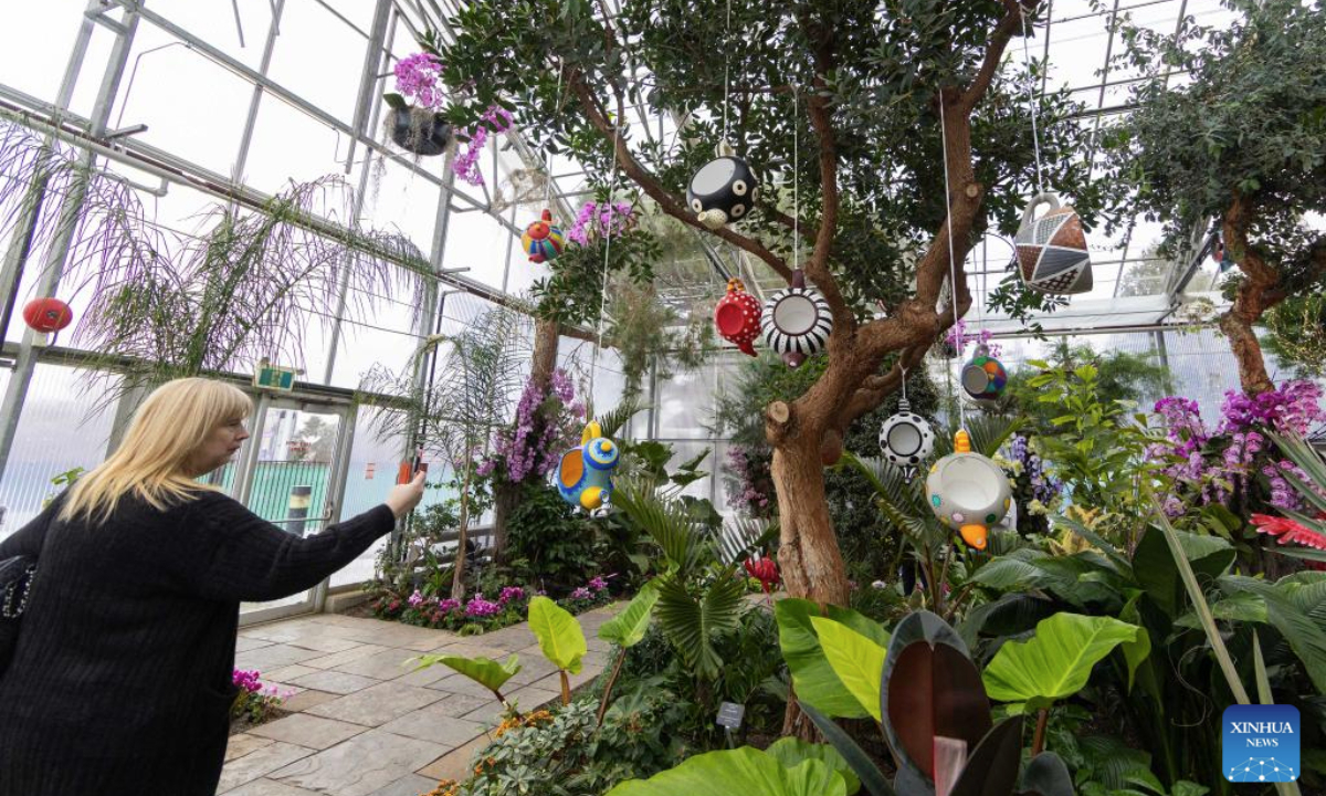A woman films a floral installation at the Alice in Bloomland exhibition at the Royal Botanical Gardens in Burlington, Ontario, Canada, on Feb. 26, 2025. Inspired by the pages of Lewis Carroll's Alice's Adventures in Wonderland, the floral exhibition is held here from Feb. 1 to March 30. (Photo by Zou Zheng/Xinhua)