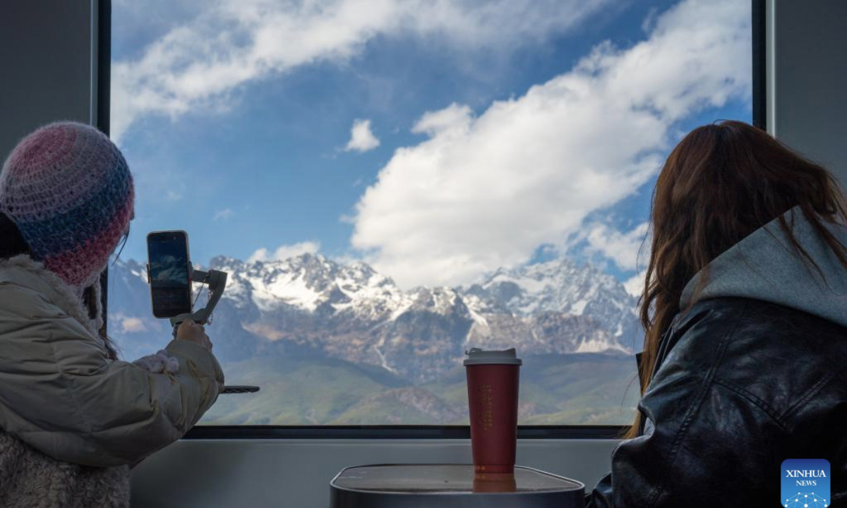 Tourists take a sightseeing train to enjoy the snow mountain scenery in southwest China's Yunnan Province, Feb. 25, 2025. A sightseeing train connecting Lijiang ancient town and Yulong Snow Mountain was launched here this February, becoming a new tourism hot spot in northwest Yunnan. (Photo by Peng Yikai/Xinhua)