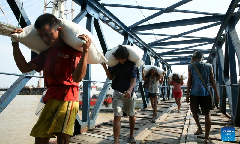 Workers carry bags of rice at a jetty in Yangon, Myanmar, March 11, 2025. Myanmar's exports of rice and broken rice in the first 11 months of the 2024-25 fiscal year reached over 2.37 million tons, according to the Myanmar Rice Federation on Tuesday. (Photo: Xinhua)