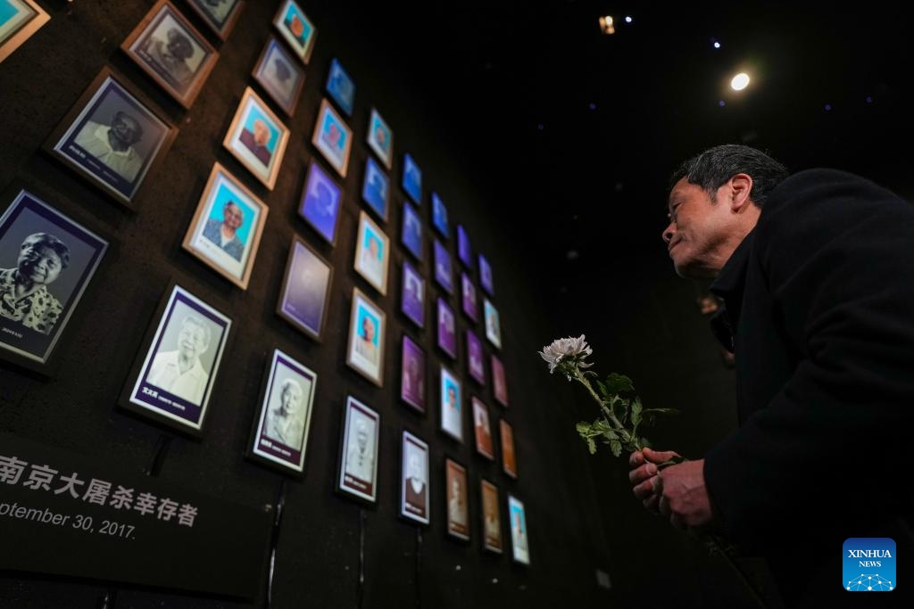 Huang Xinghua, son of Nanjing Massacre survivor Ai Yiying, lays a flower at a lights out mourning ceremony held at the Memorial Hall of the Victims in Nanjing Massacre by Japanese Invaders, in Nanjing, east China's Jiangsu Province, March 11, 2025. A lights out mourning ceremony for four survivors of the Nanjing Massacre who passed away this year was held Tuesday in Nanjing. (Photo: Xinhua)