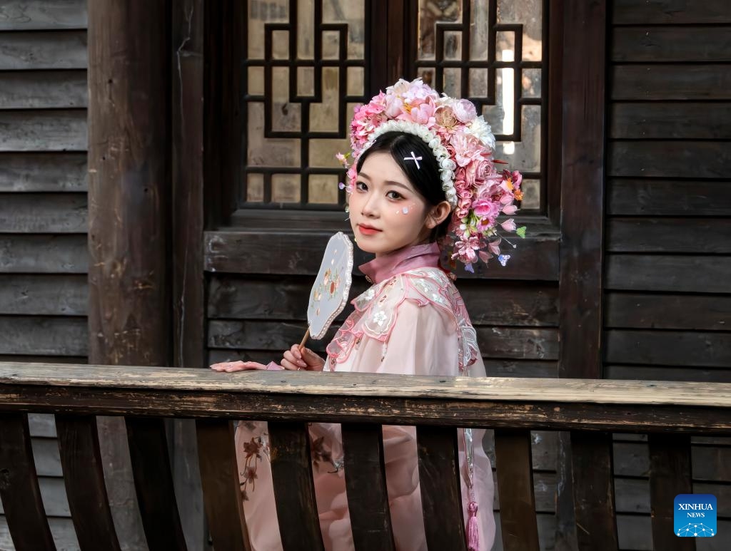 A tourist wearing flowery headwear poses for photos in Fuzhou, southeast China's Fujian Province, Feb. 3, 2025. Fuzhou is home to a rich intangible cultural heritage, including Shoushan stone carvings, Fuzhou bodiless lacquerware, wood carvings, and oil-paper umbrellas, etc. In recent years, Fuzhou has been exploring new pathways in the inheritance and innovation of intangible cultural heritage. (Photo: Xinhua)