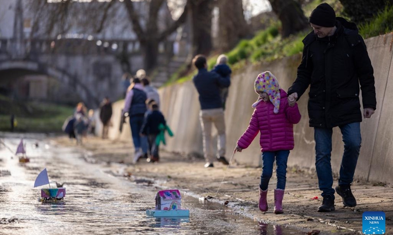 A girl walks with her father next to their homemade miniature boats floating down the stream during an event to celebrate the arrival of spring in Ljubljana, Slovenia on March 11, 2025. (Photo: Xinhua)