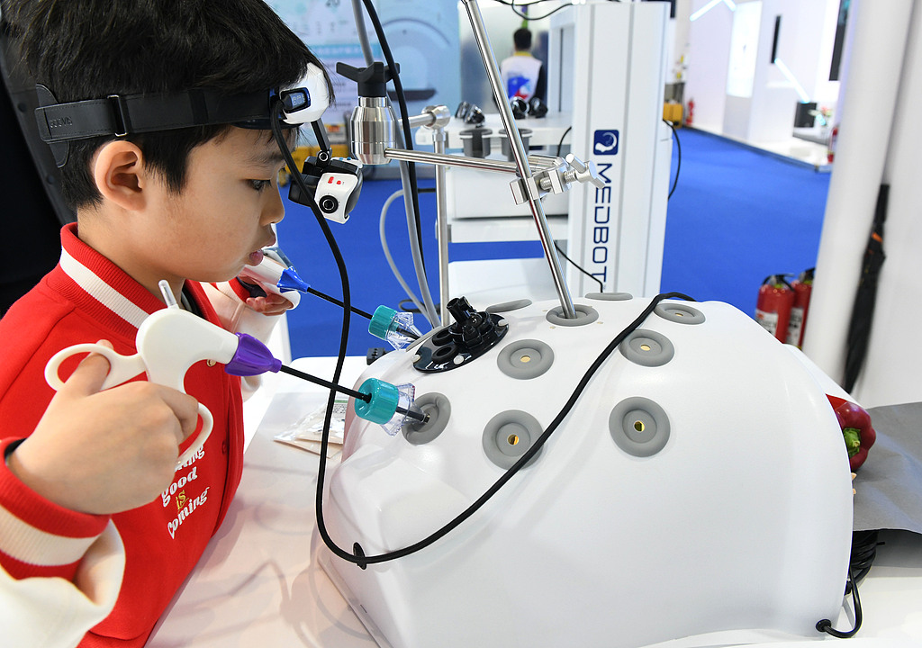 A kid experiences simulated laparoscopic surgeries through virtual reality (VR) technology, at the 2025 Medical Equipment Exhibition in Southwest China's Chongqing Municipality, on March 14, 2025. This year's exhibition is divided into 34 specialized zones, and more than 10,000 new products, technologies, applications, and methods in the medical equipment field are on display, showcasing the latest advancements and innovations in the industry. Photo: VCG