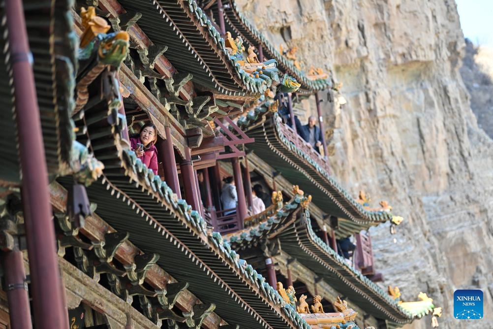 Tourists visit the Hanging Temple, or Xuankong Temple, in Hunyuan County, Datong City in north China's Shanxi Province, on Feb. 28, 2025. Built over 1,500 years ago, the temple is notable for its location on a sheer precipice. The structure is kept in place with wooden beams inserted into holes chiseled into the cliffs. The main supportive structure is hidden inside the bedrock. The temple is located in a deep valley, and the body of the building hangs from the side of a cliff under a prominent peak, protecting the temple from rain erosion and sunlight. (Photo: Xinhua)