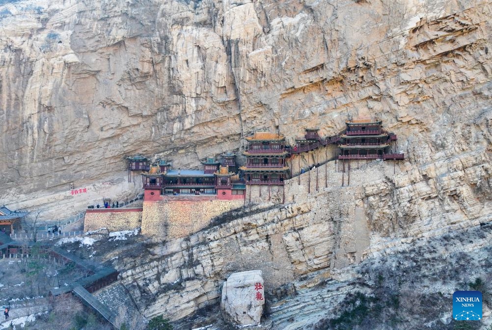 An aerial drone photo taken on Feb. 28, 2025 shows the Hanging Temple, or Xuankong Temple, in Hunyuan County, Datong City in north China's Shanxi Province. Built over 1,500 years ago, the temple is notable for its location on a sheer precipice. The structure is kept in place with wooden beams inserted into holes chiseled into the cliffs. The main supportive structure is hidden inside the bedrock. (Photo: Xinhua)