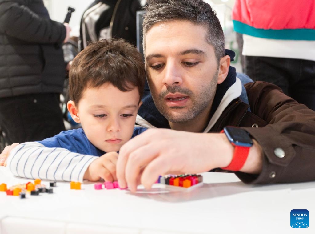 A boy and his father take part in a LEGO Mural Building event in Toronto, Canada, on March 17, 2025. LEGO Canada invited people to build a hockey-themed LEGO mural with 41,472 LEGO bricks here on Monday. (Photo: Xinhua)