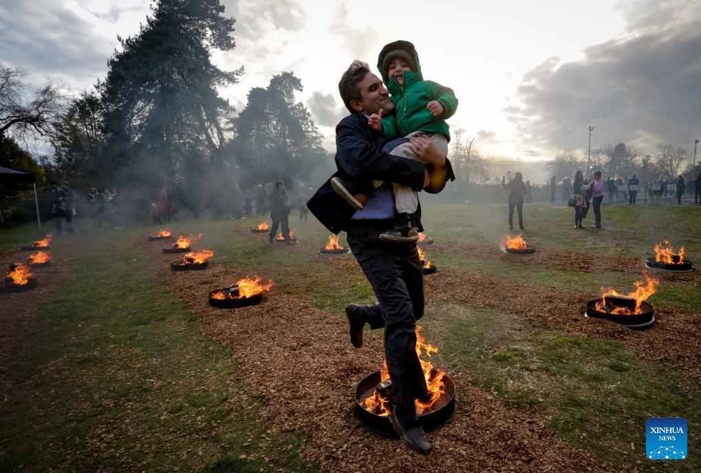 A man leaps over a bonfire with his child during a fire festival at Ambleside Park in West Vancouver, British Columbia, Canada, March 18, 2025. The local Iranian community participated in the fire festival on Tuesday to celebrate the upcoming Nowruz, the Iranian New Year, which falls on March 20 this year. (Photo: Xinhua)