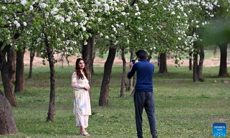A woman poses for photos with flowers in Islamabad, Pakistan, on March 19, 2025. (Photo: Xinhua)