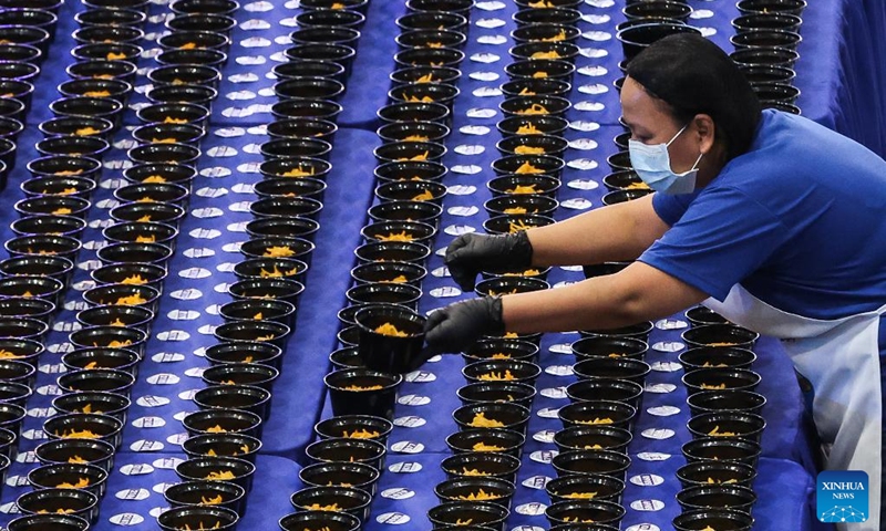A volunteer arranges the noodle bowls during Malabon City's attempt to break the Guinness World Record for the longest line of bowls of noodles in Malabon City, the Philippines, on March 21, 2025. The city successfully achieved the Guinness World Record for the longest line of bowls of noodles with 6,549 bowls. Photo: Xinhua