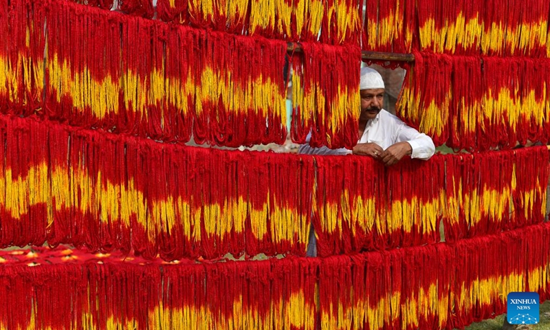 An artisan hangs freshly dyed kalawa thread, a traditional sacred thread used in Hindu rituals, at a village in Prayagraj of India's northern state of Uttar Pradesh, March 21, 2025. Photo: Xinhua