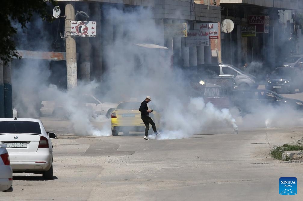 A Palestinian tries to kick a tear gas canister during clashes with Israeli forces in the Balata refugee camp, east of Nablus in the northern West Bank, on March 24, 2025. (Photo: Xinhua)