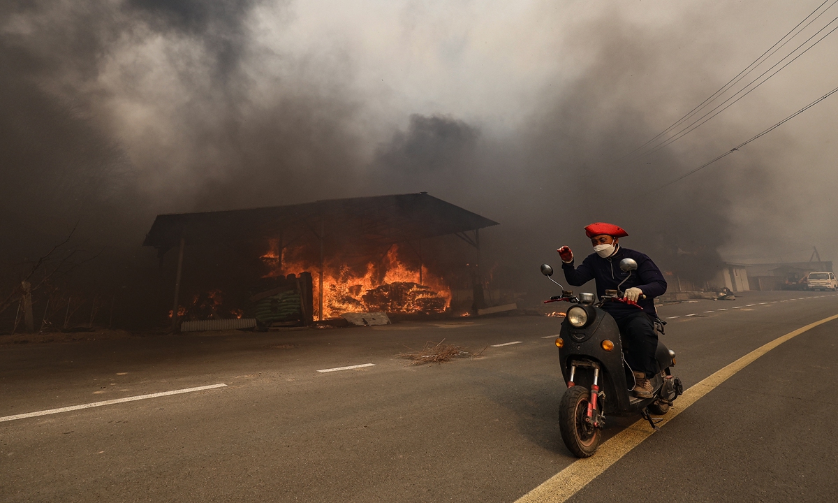 A resident evacuates from wildfires in Uiseong, North Gyeongsang Province, South Korea, on March 25, 2025. At least four people have been killed and more than 3300 people forced to flee their homes since blazes broke out in several areas on March 22. The deadly wildfires, which intensified on March 24, prompted authorities to designate three additional counties as 