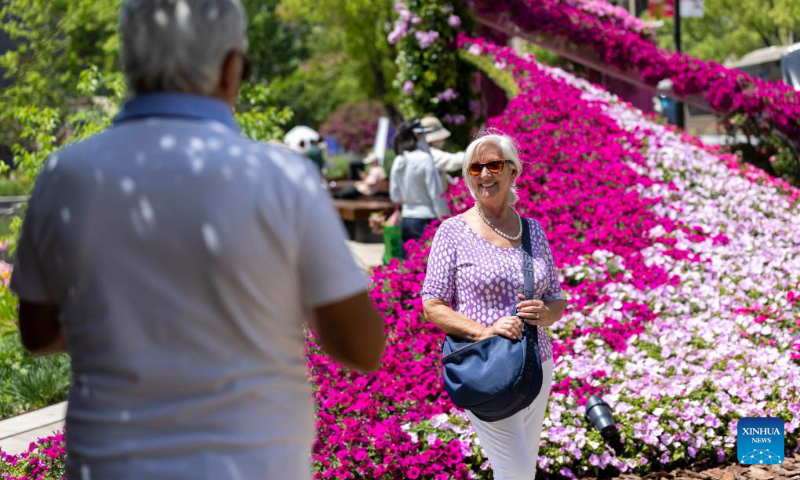A foreign tourist poses for photos with flowers at a venue of the 2025 Shanghai International Flower Show in Huangpu District of east China's Shanghai, April 18, 2025. The 2025 Shanghai International Flower Show opened on Friday with two main venues, five sub-venues and 15 exhibition spots across the city. (Xinhua/Wang Xiang)