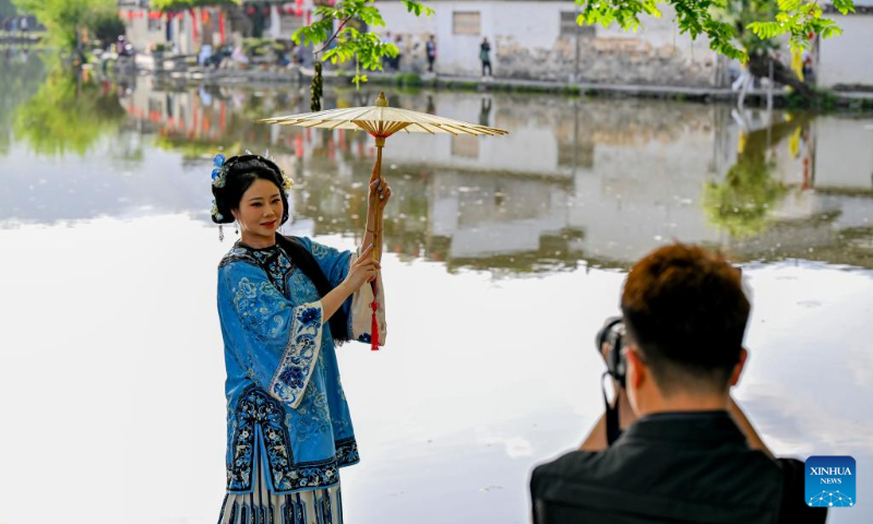 A tourist poses for photos in Hongcun Village of Yixian County, Huangshan City, east China's Anhui Province, April 17, 2025. (Xinhua/Xu Jiayi)